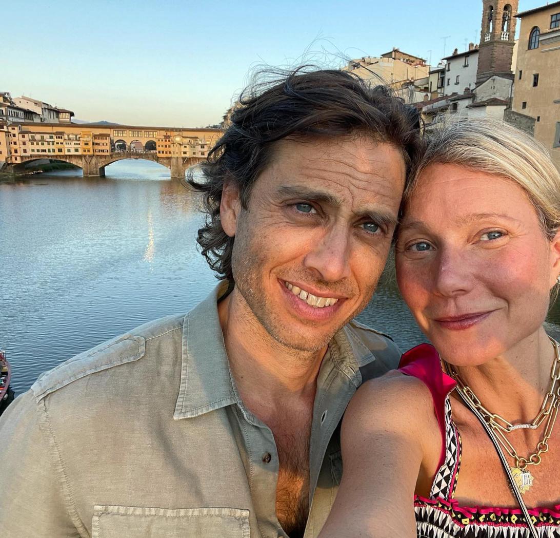 Гвинет Пэлтроу с мужем Брэдом Фэлчаком делают селфи, улыбаясь на фоне знаменитого моста Понте Веккьо.