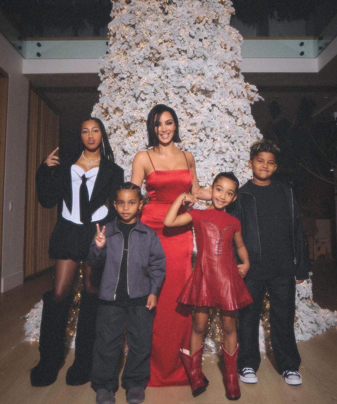 Ким Кардашьян с четырьмя детьми на фоне белой рождественской елки.