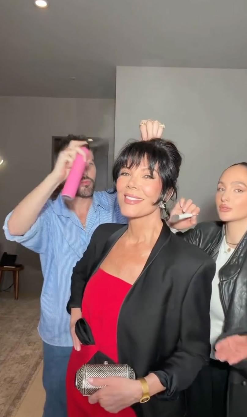 Над прической Крис Дженнер колдуют двое: один распыляет лак, другой расчёсывает.