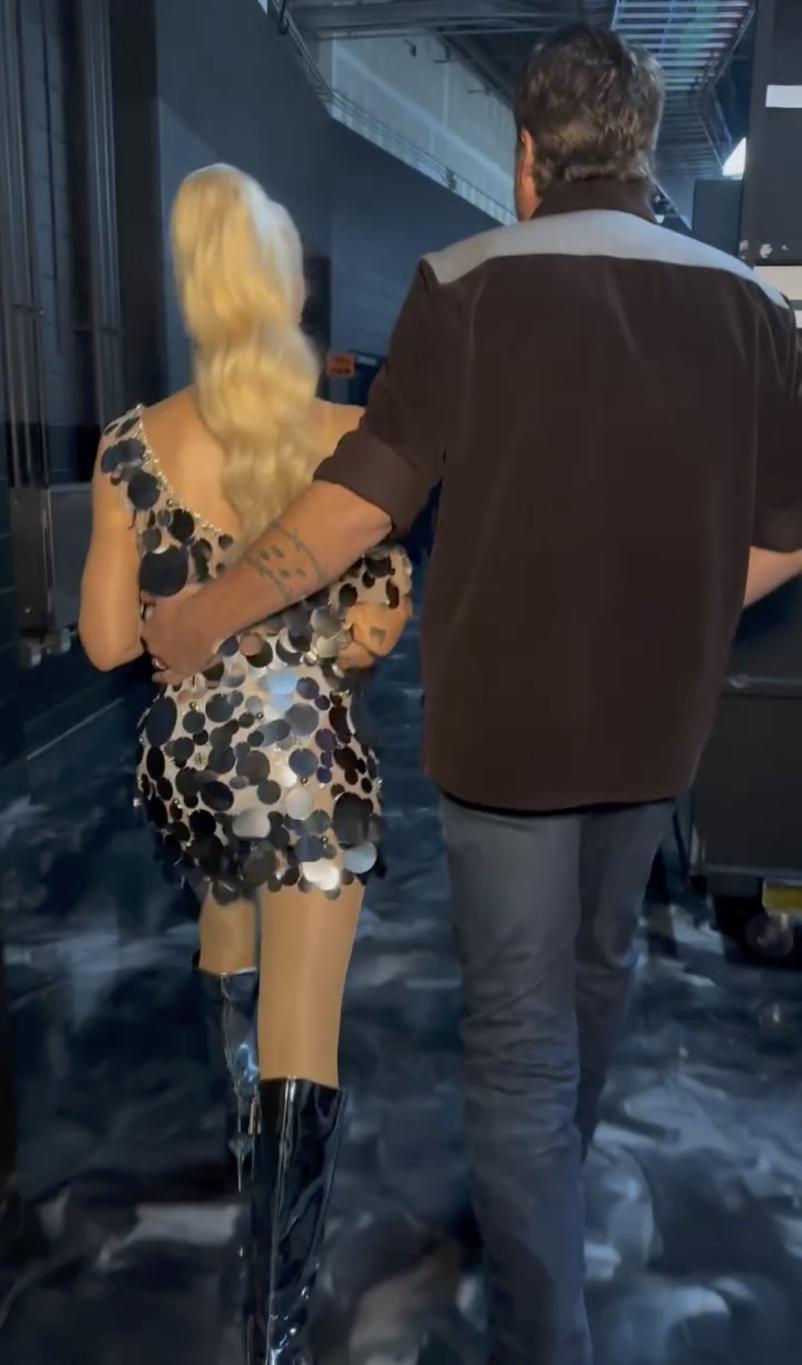 Гвен Стефани и Блейк Шелтон, спиной к камере, удаляются вдаль.