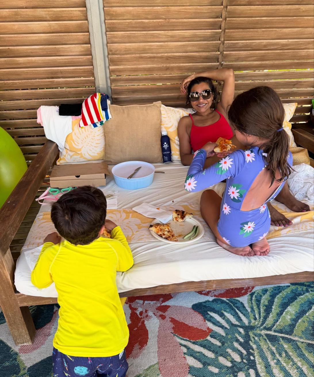 Минди Калинг с детьми на кушетке наслаждается пиццей.