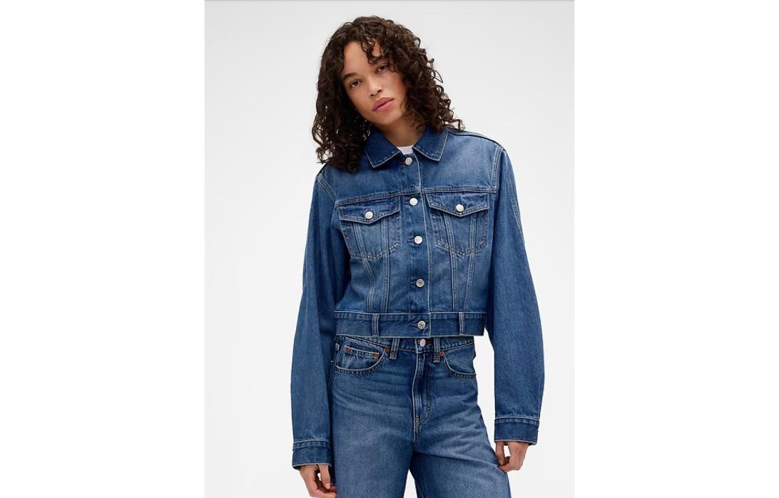 Брюнетка с кудрями в джинсовой куртке и джинсах.