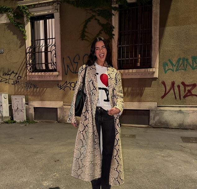 Дуа в пальто с принтом крокодила, футболке "Я люблю Нью-Йорк" и черных джинсах.