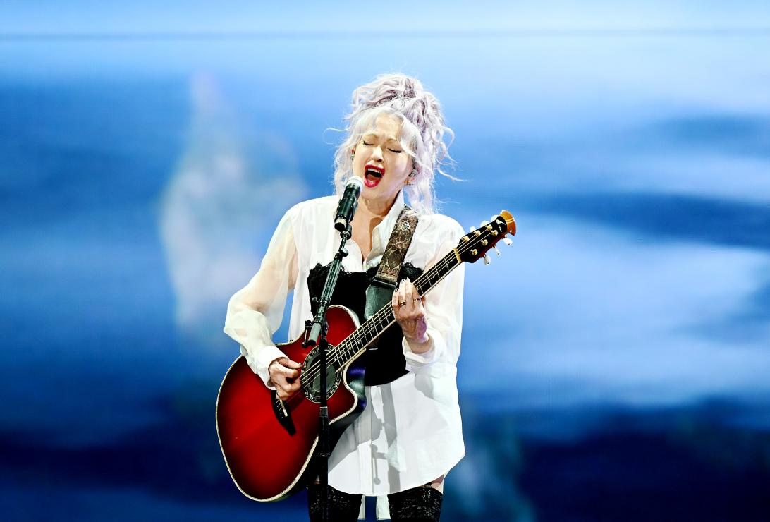 Синди Лопер вживую с акустической гитарой и микрофоном.