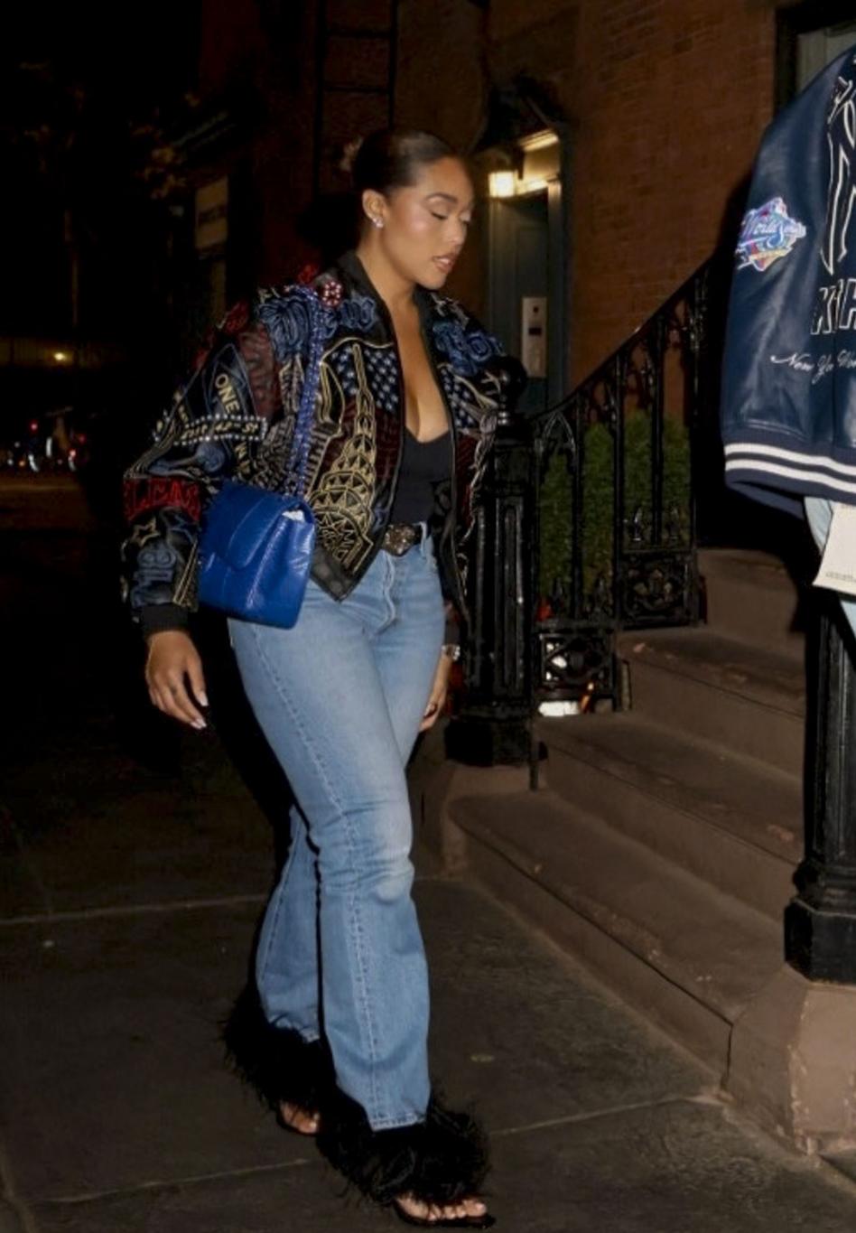 Джордин Вудс в черном бомбере, синих джинсах и черных меховых туфлях с голубой сумкой.