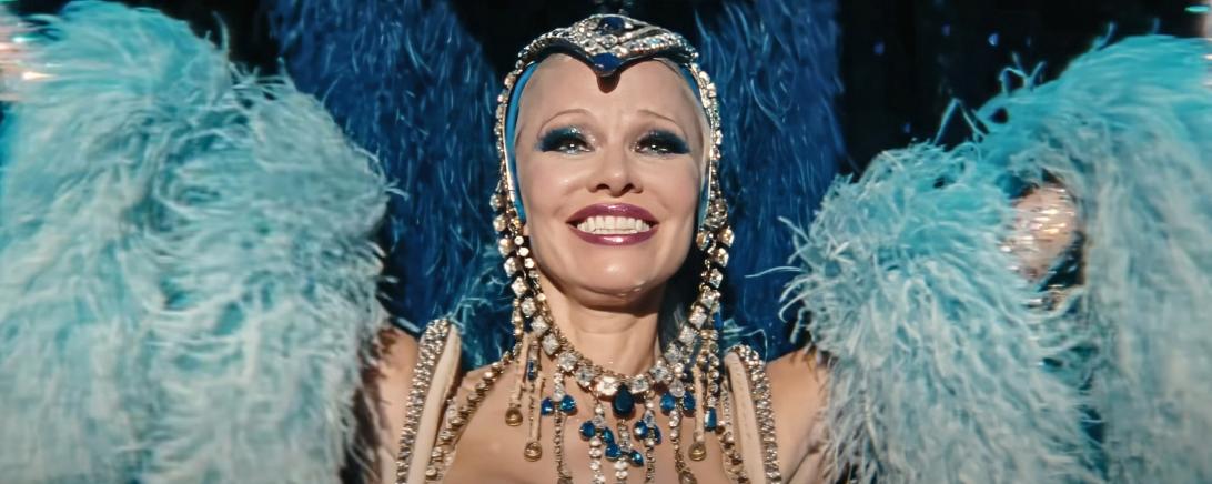 Памела Андерсон - шоугёрл в блестящем костюме и голубом пернатом головном уборе.