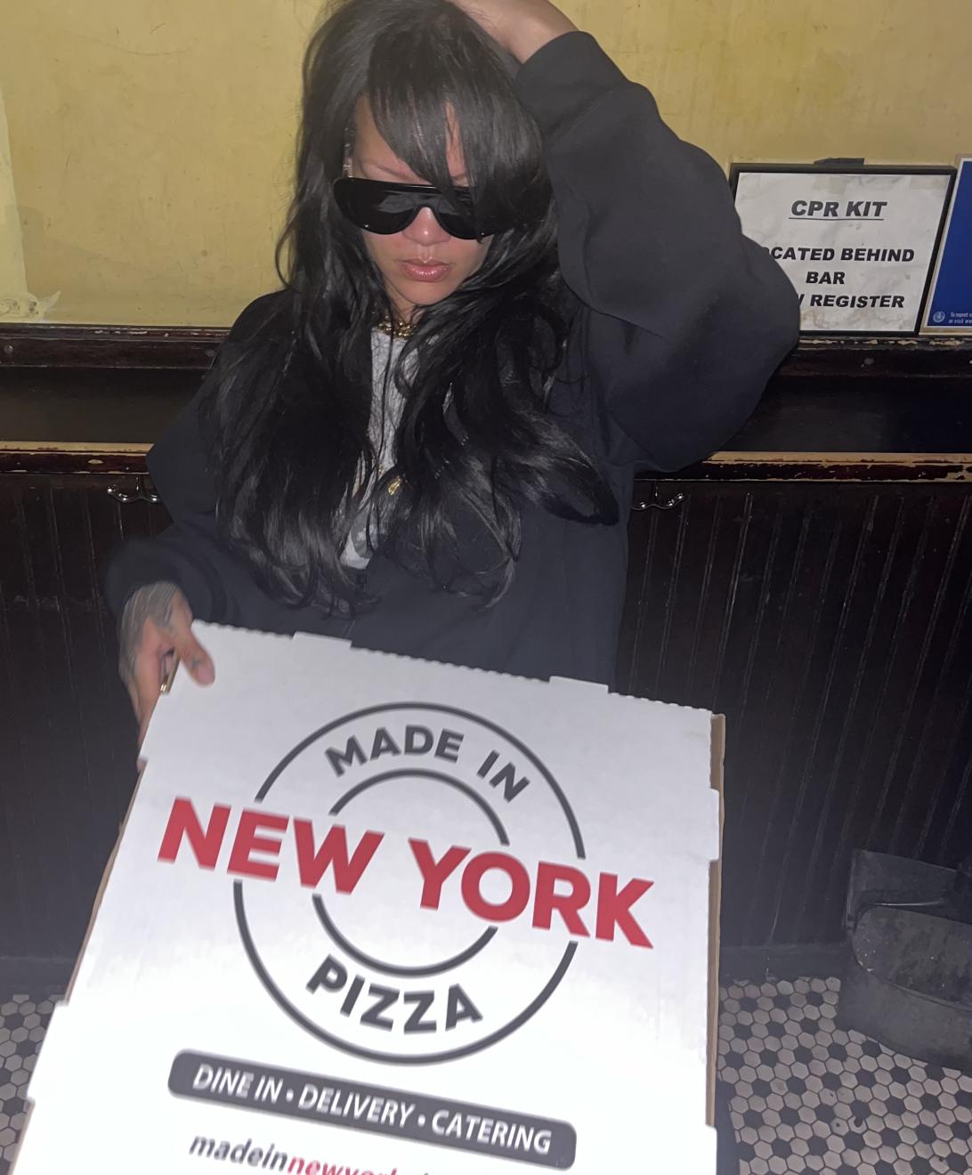 Рианна в темных очках держит коробку пиццы из "Made in New York Pizza".