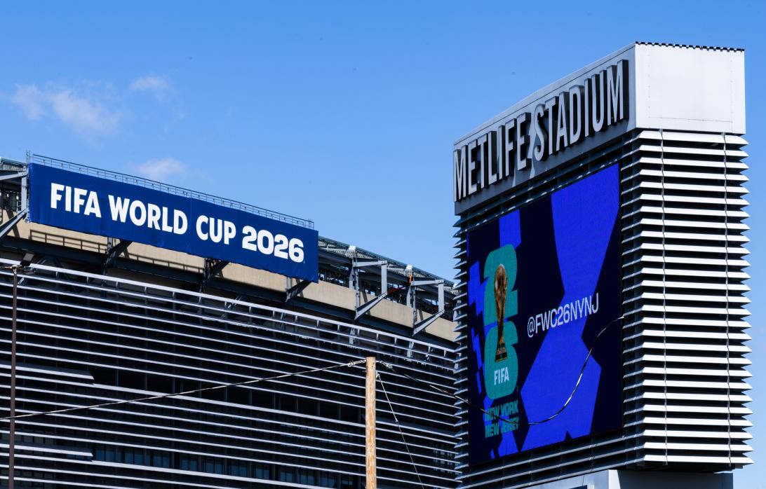 Стадион MetLife с баннером "ЧМ-2026" и экраном, демонстрирующим трофей и "@FWC26NVNJ".